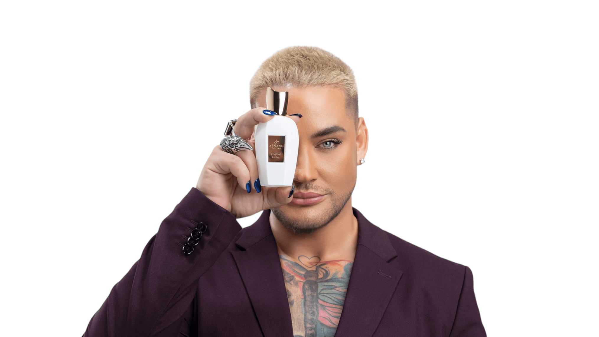 Daniel René holding Ainash Parfums’ Coconut Candy extrait de parfum — white bottle with gold label against light gray background.